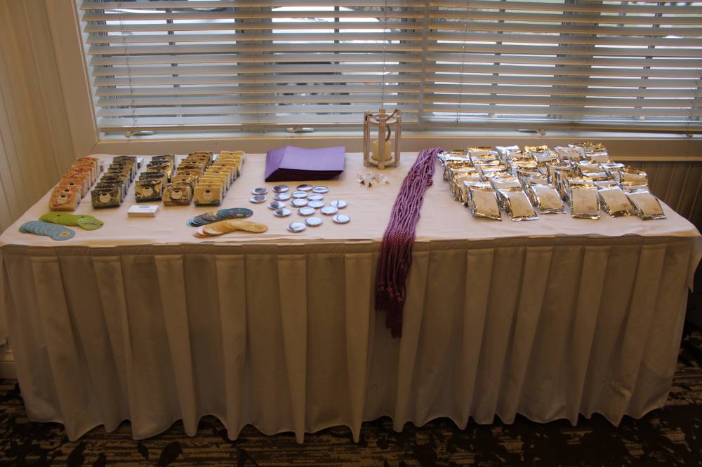 a photo of a table with purple Triota graduation cords, soaps and coffee beans from local vendors, and WGS stickers and buttons